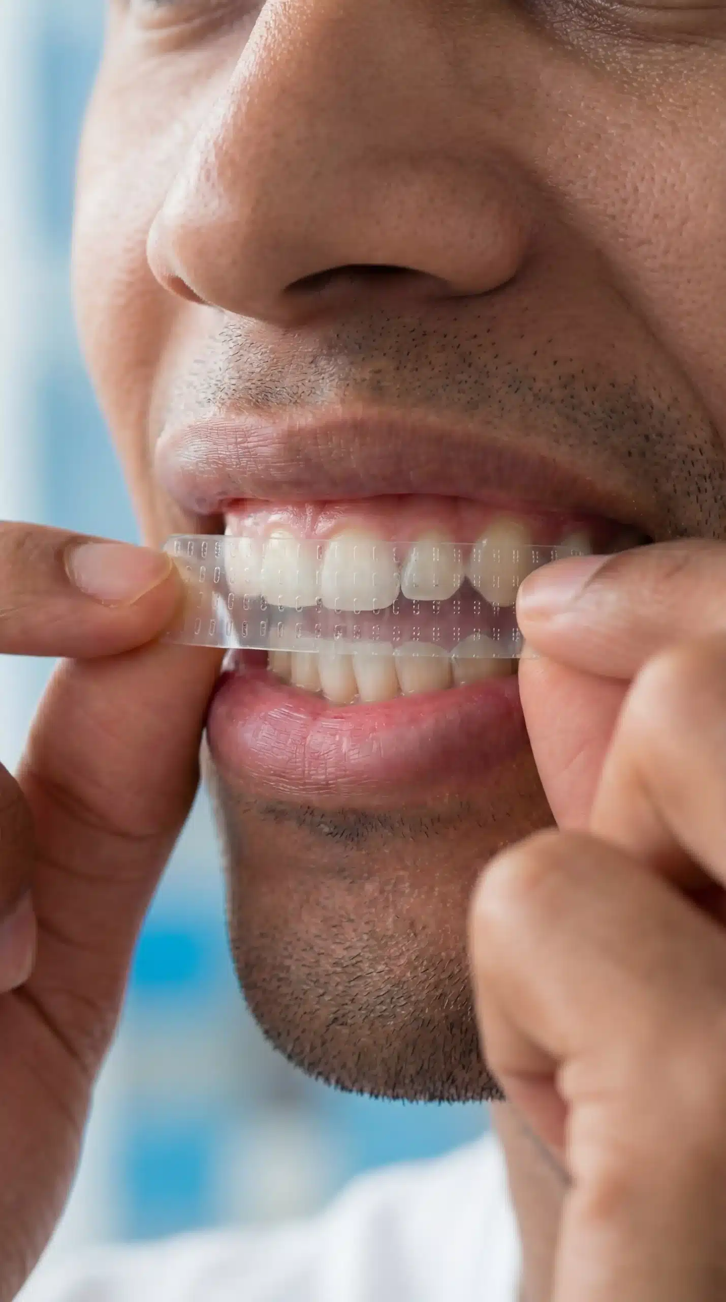 Person applying an OraCare White whitening strip