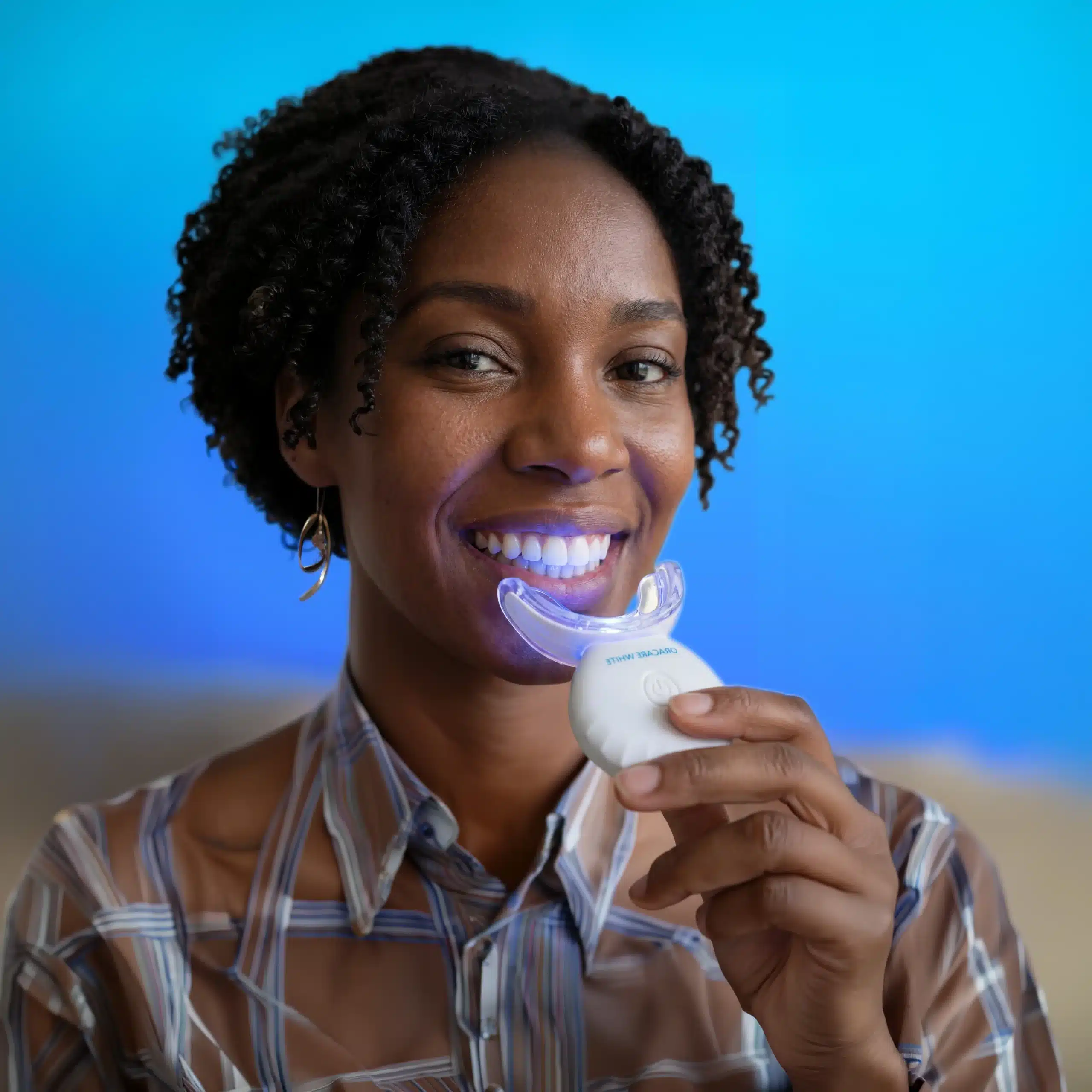 Woman using the OraCare White LED whitening kit